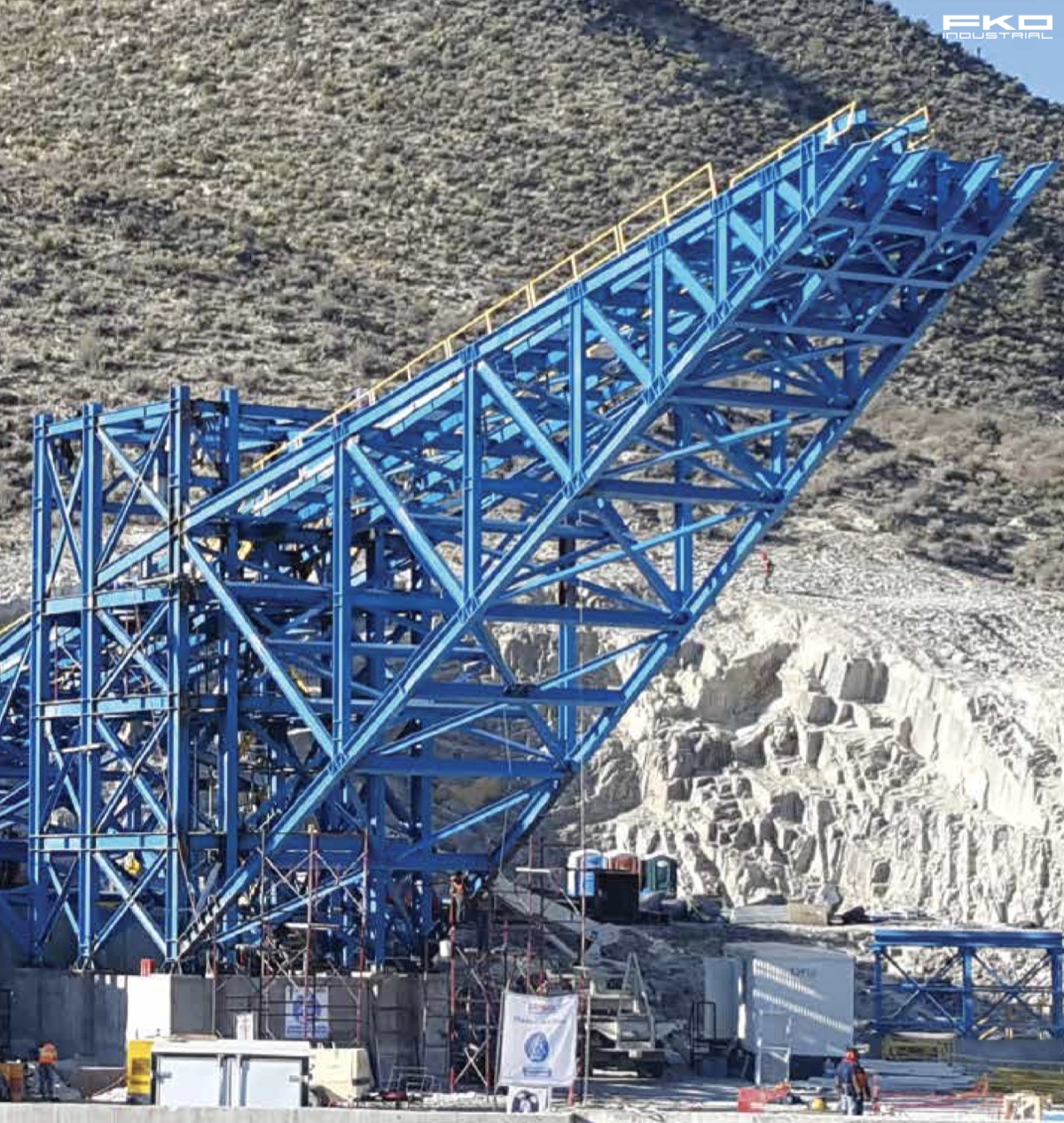 Puente transportador de acero azul montado sobre ladera en obra minera